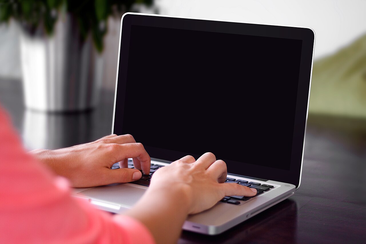 Tangan mengetik di keyboard laptop untuk mengirim pesan